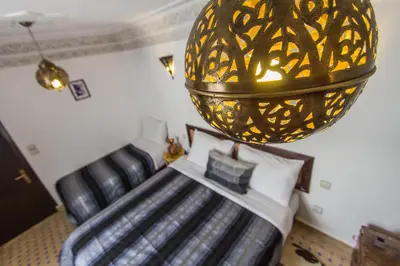a bedroom with a bed with a gold chandelier at Riad Taha in Fès