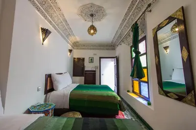 a bedroom with two beds and a mirror at Riad Taha in Fès