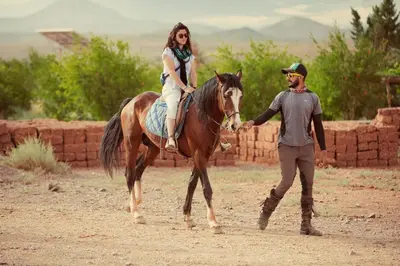 a man is leading a woman on a horse at Ecolodge l'île de Ouarzazate in Ouarzazate