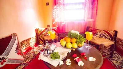 a table with a bowl of fruit and two glasses of orange juice at Ecolodge l'île de Ouarzazate in Ouarzazate