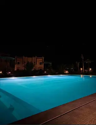 a large blue swimming pool at night at Ecolodge l'île de Ouarzazate in Ouarzazate