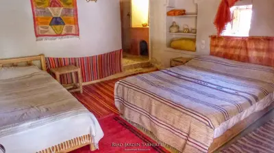 a bedroom with two beds and a window at Riad Tabhirte in Agdz