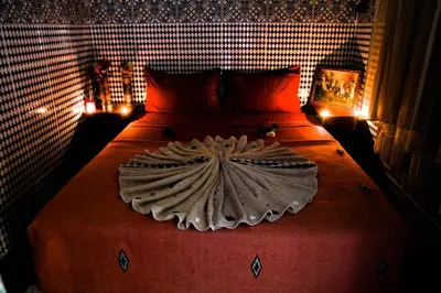 a bedroom with a large bed with red sheets and lights at Dar Berrada-Ziat in Fès