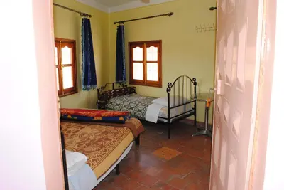 a bedroom with two beds and a chair in it at Auberge Restaurant Rooftop Tamazirt in Boumalne