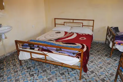 a small bedroom with a bed and a sink at Auberge Restaurant Rooftop Tamazirt in Boumalne