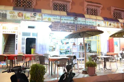 a restaurant with tables and chairs and umbrellas at Auberge Restaurant Rooftop Tamazirt in Boumalne