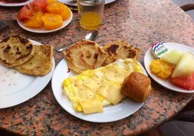 a table with plates of eggs and toast and fruit at Auberge Restaurant Rooftop Tamazirt in Boumalne