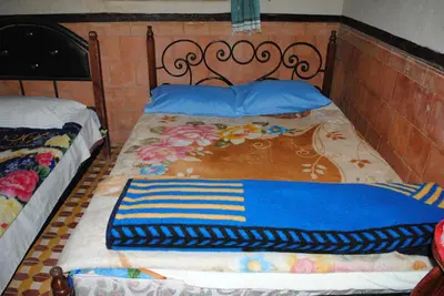 two beds with blue pillows and a blanket on them at Auberge Restaurant Rooftop Tamazirt in Boumalne