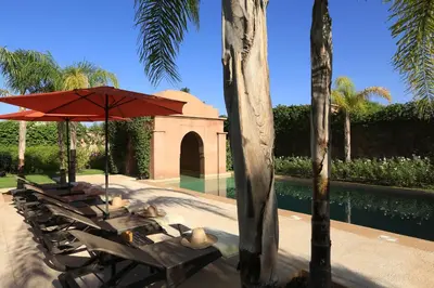 a group of chairs with an umbrella next to a pool at Villa Jannah in Marrakech