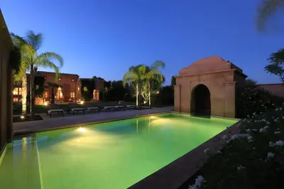 a swimming pool with green water at night at Villa Jannah in Marrakech