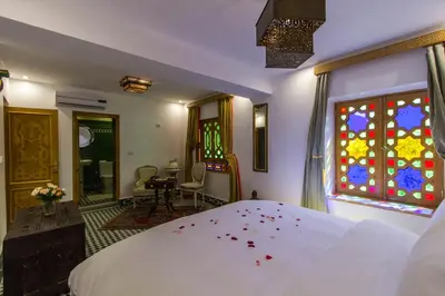 a bedroom with a white bed and stained glass windows at Riad Amor - Suite & Spa in Fès