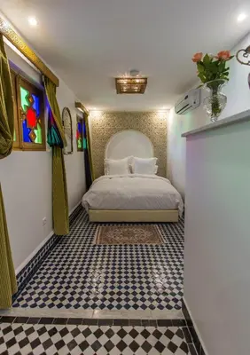 a bedroom with a bed and a checkered floor at Riad Amor - Suite & Spa in Fès
