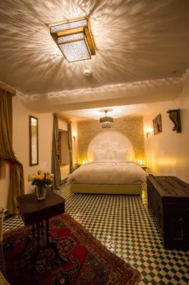 a bedroom with a large bed and a table at Riad Amor - Suite & Spa in Fès