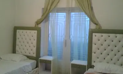a bedroom with two beds and a window with curtains at Hotel School Ersat Azrou in Azrou