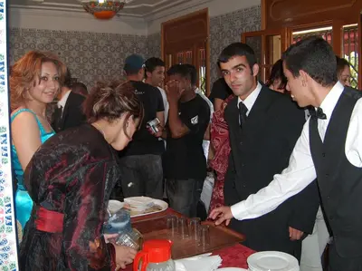 a group of people standing around a table cutting a cake at Hotel School Ersat Azrou in Azrou