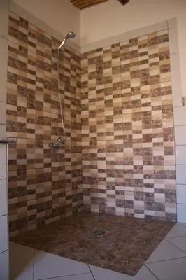 a bathroom with a shower with a tiled wall at Riad Amodou in Tinerhir