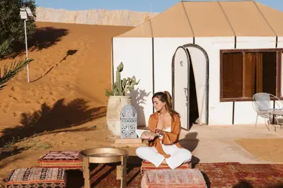 a woman sitting in front of a tent at Caravanserai Luxury Desert Tented Camp in Merzouga