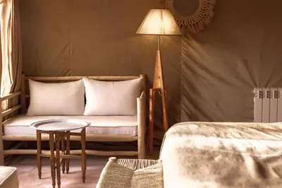 a room with a couch and a table and a lamp at Caravanserai Luxury Desert Tented Camp in Merzouga