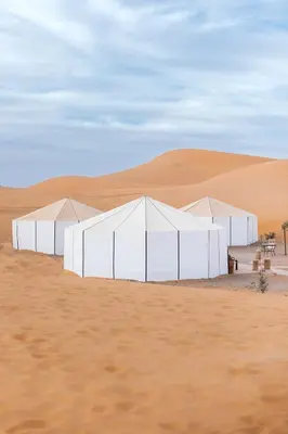 a group of white tents in the desert at Caravanserai Luxury Desert Tented Camp in Merzouga