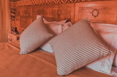 a bed with two pillows on top of it at Caravanserai Luxury Desert Tented Camp in Merzouga