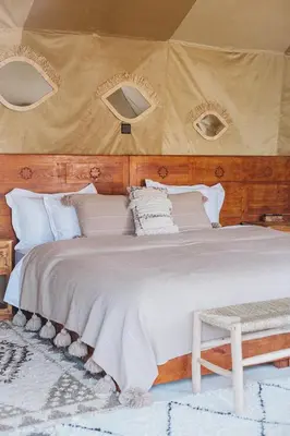 a bedroom with a large bed with a wooden headboard at Caravanserai Luxury Desert Tented Camp in Merzouga