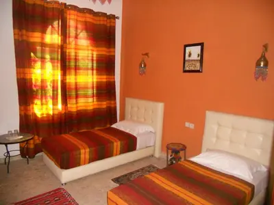 two beds in a room with orange walls at Riad Passiflora in Fès