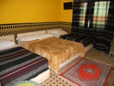 a room with two beds and a table and a couch at Riad Passiflora in Fès