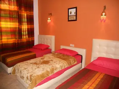 two beds in a room with orange walls at Riad Passiflora in Fès