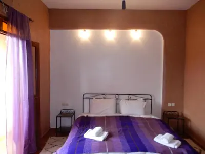 a bedroom with a bed with two white shoes on it at Riad Tazawa in Ibrahene