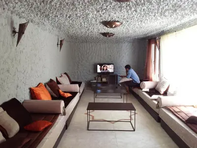 a man sitting on a couch in a living room at Riad Tazawa in Ibrahene