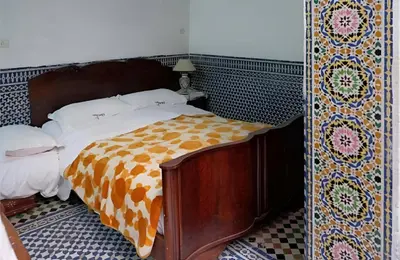 a bed in a room with a patterned wall at Dar El Arfaoui in Fès