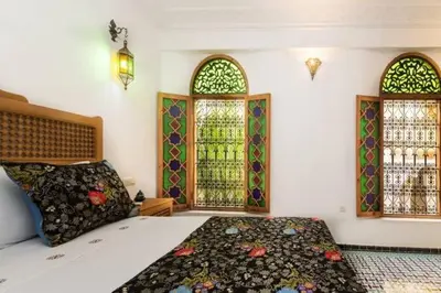 a bedroom with a bed and two stained glass windows at Riad Vega in Fès