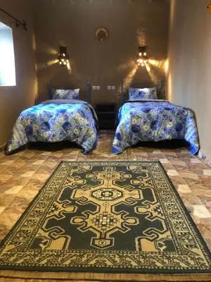 a bedroom with two beds and a rug on the floor at Riad Marhaba Merzane in Merzane