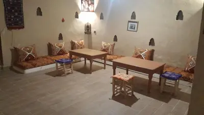 a living room with a couch and a table and chairs at Riad Marhaba Merzane in Merzane