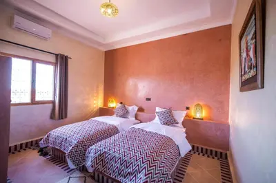 a bedroom with two beds and a window at Riad Les jardins de Merzouga in Merzouga