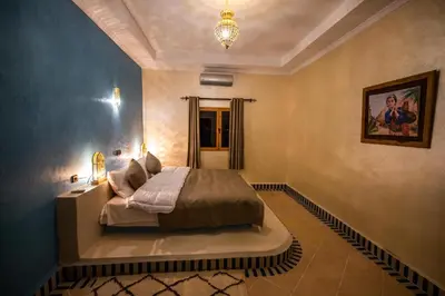 a bedroom with a bed and a chandelier at Riad Les jardins de Merzouga in Merzouga