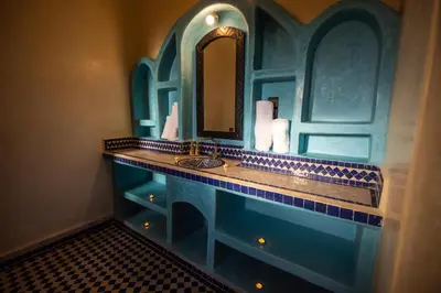 a blue bathroom with a sink and a mirror at Riad Les jardins de Merzouga in Merzouga