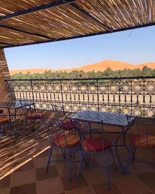 a patio with tables and chairs and a view at Riad Les jardins de Merzouga in Merzouga