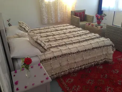 a large bed in a room with a table at Maison La Berberina in Goulmima
