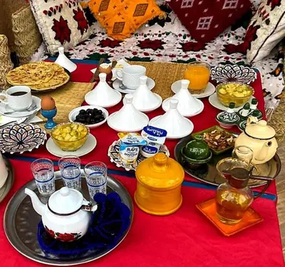 a table with tea pots and cups on a red table cloth at Maison La Berberina in Goulmima