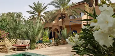 a resort with a chair and palm trees and a swimming pool at Maison La Berberina in Goulmima