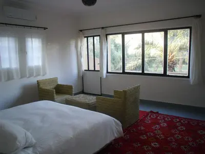 a bedroom with a bed and two chairs and a window at Maison La Berberina in Goulmima