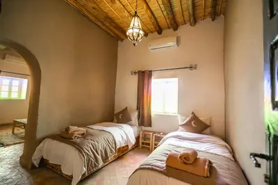 a bedroom with two beds in a room with a window at Riad Kasbah Aiour in Merzouga