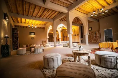a large room with tables and chairs in a building at Riad Kasbah Aiour in Merzouga