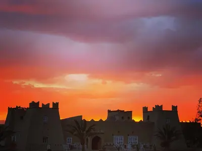 a silhouette of a castle with a sunset in the background at Riad Kasbah Aiour in Merzouga