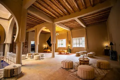 a large room with tables and chairs in a building at Riad Kasbah Aiour in Merzouga
