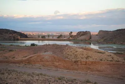 a river in the middle of a desert with mountains at Appartement Anatim in Ouarzazate