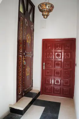 a room with two red doors and a chandelier at Appartement Anatim in Ouarzazate