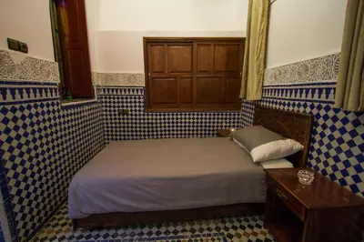 a small bedroom with a bed with blue and white tiles at Dar El Mathaf FES in Fès