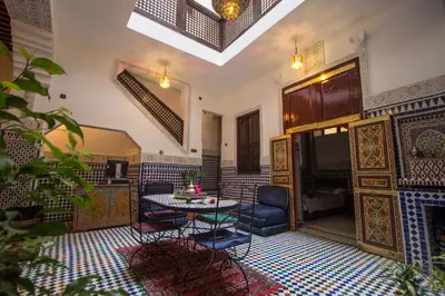 a living room with a table and chairs in a room at Dar El Mathaf FES in Fès